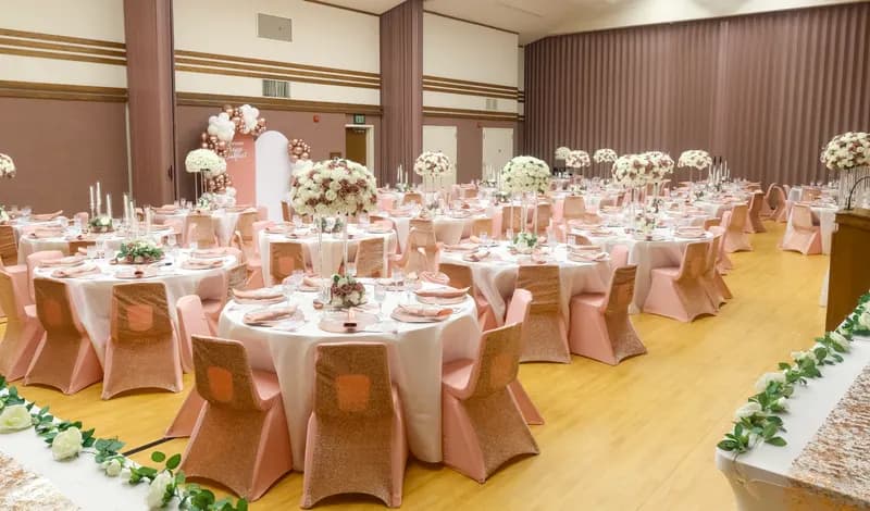 Full venue transformation: blush and ivory tables, rose-gold chairs and greenery garland along the head table