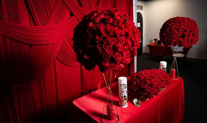 Tall red rose ball centerpieces on gold stands beside a red-draped head table