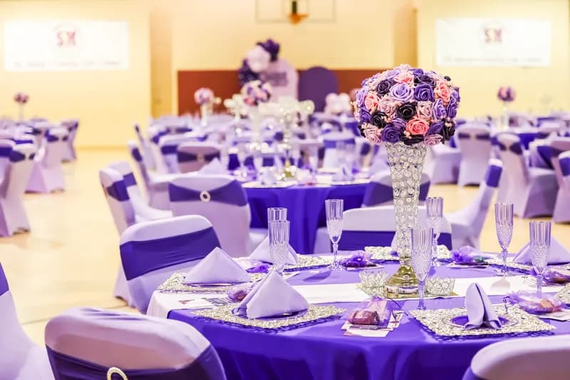Prayer breakfast tables in purple and lavender with crystal vases of purple roses