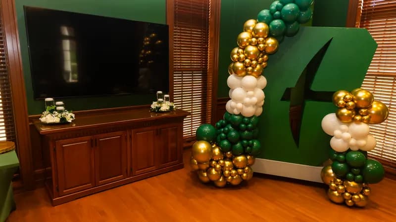 Emerald, white and gold balloon garland around a green marquee letter